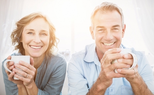 Smiling middle aged couple sitting on the couch having coffee