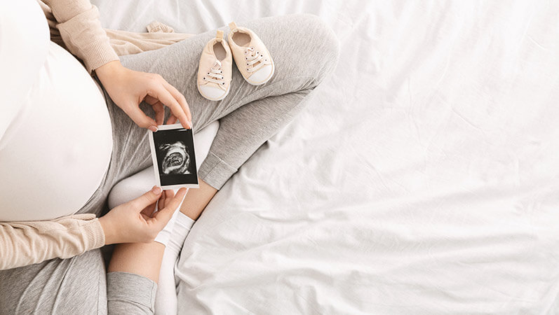 Pregnant woman enjoying future motherhood with first ultrasound photo